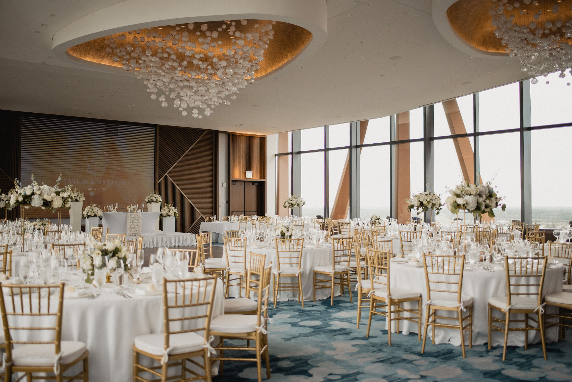 Reception ballroom dressed in white florals and gold accents