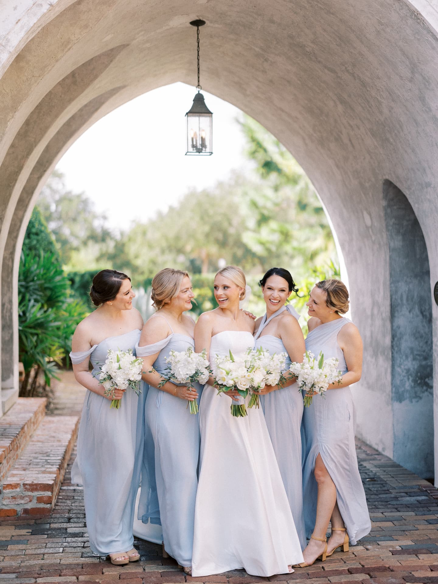 Bride and bridesmaids beneath a stone arch